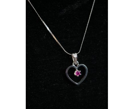 A 18 carat white gold openwork heart pendant and snake chain. The pendant set with a round mixed cut ruby with an approximate