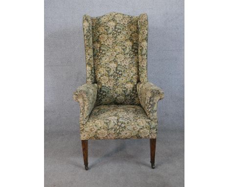 A 19th century wingback armchair, upholstered in tapestry style foliate fabric, raised on figured walnut square section taper