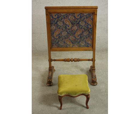 A William IV walnut fire screen with Paisley fabric panels, the legs joined by a turned stretcher, the bases with scrolling b