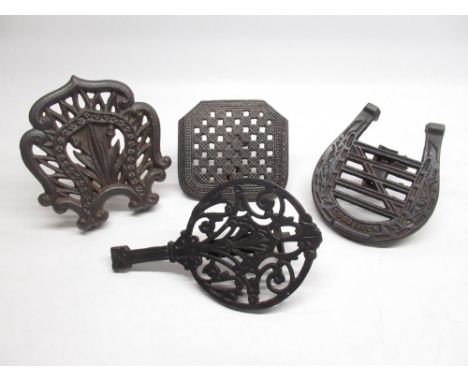 Four cast metal trivets, one depicting a horseshoe with gate in-between and the words 'Good Luck' 