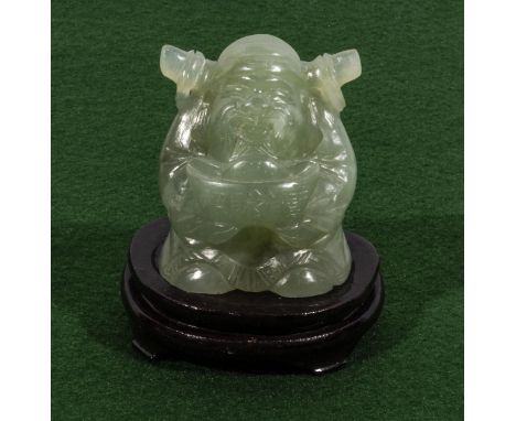 A small jade Buddha on wood stand