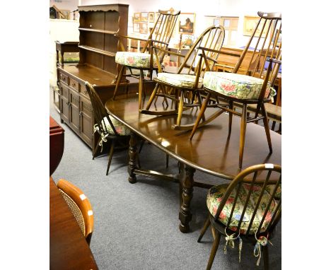 An Ercol dark elm extending dining table together with six matching stick back dining chairs including two carvers, a matchin