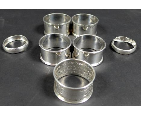 A collection of seven George V silver napkin rings, comprising a pair of napkin rings with reeded bands, one engraved Jean, t