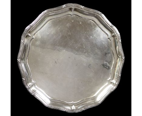 An Edwardian silver tray, of circular form with Chippendale pie crust edge, raised on three stepped hoof feet, marks rubbed, 