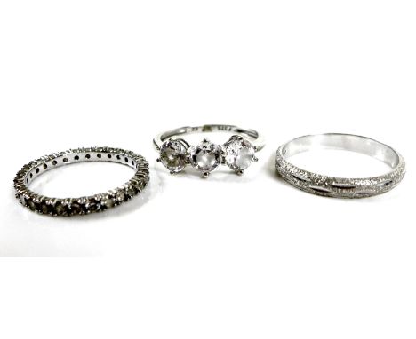 An 18ct white gold wedding band, with textured surface, size N, 2.4g, together with a 9ct white gold ring set with three whit
