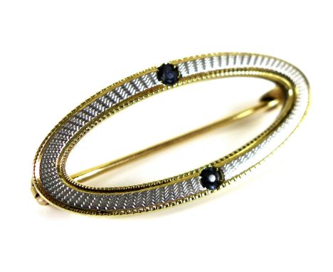A 14ct gold brooch set with engine turned white gold and two sapphires, open oval design, 2.7cm, 2g. 