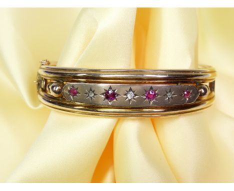 A 9CT GOLD DOUBLE LOOP BANGLE - with safety chain and a half band of three small diamonds and three rubies, 16grms gross
