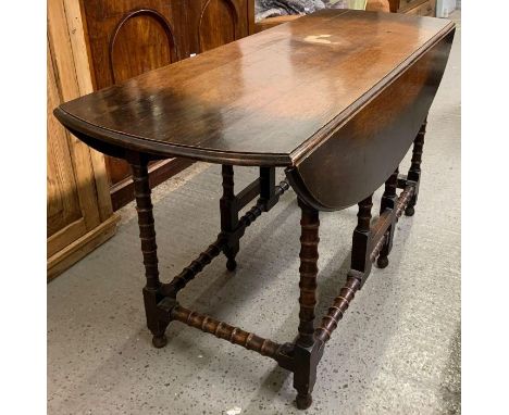 A 20th century stained oak gate leg wake table with two drop leaves, standing on turned legs, 70cm high, 127cm long, 104cm di