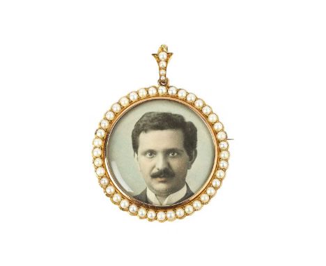 A half pearl locket brooch/pendant, designed as a circular glazed aperture bordered by half pearls, below a similarly set fol