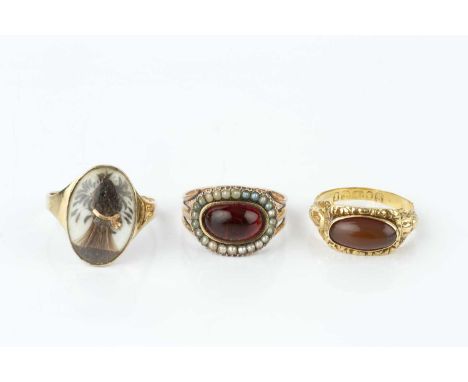 Three Georgian panel rings, the first an 18ct gold and cabochon set memorial ring, profusely carved with shells, scrolls and 