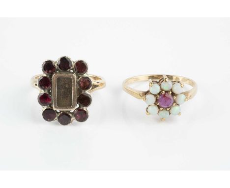 Two gem set rings, comprising a garnet set panel ring, the central aperture bordered by circular mixed-cut garnets in foiled 