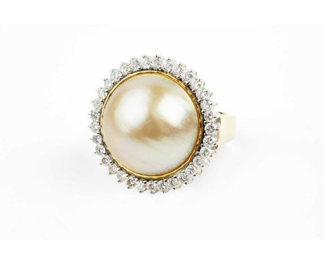 A mabe pearl and diamond cluster ring, the mabe pearl of yellowish hue, measuring approximately 18.4mm diameter, bordered by 