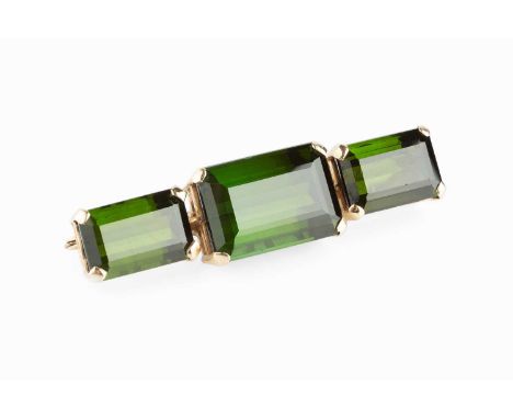 A green tourmaline three stone brooch, the rectangular step-cut tourmalines in four claw settings, each with pierced gallery,