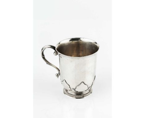 A silver christening mug, with slightly flared rim, and scroll handle, the gadrooned base with raised stylised decoration, by