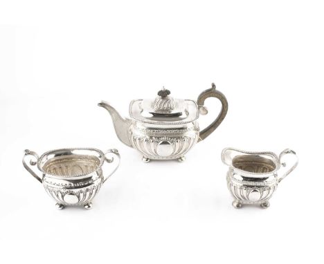 A late Victorian silver three piece tea service, with half lobed and embossed decoration, and gadrooned borders, the teapot w