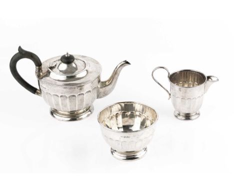 A silver three piece tea service, with faceted circular bodies, the teapot with ebonised handle and knop, by Viner's Ltd, She