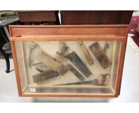 Glass display case with various vintage tools, planes, saws, levels etc