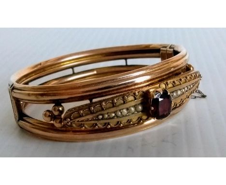 An Edwardian 9ct yellow gold bangle with mounted ruby-coloured stone and seed pearl decoration by S Ward & Sons, Chester, 190