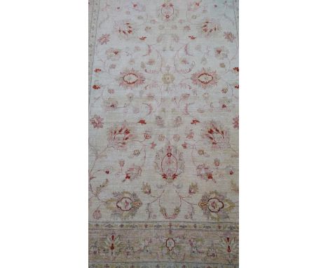 A Ziegler ivory-ground hand-knotted Pakistani wool rug with multicoloured floral decoration, wide border and short fringe, 26