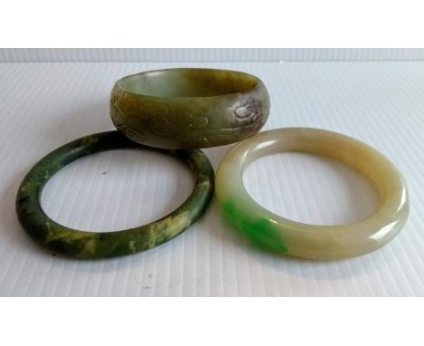 A carved Chinese jade bangle, 6cm internal diameter and two others, 6, 5.5cm internal diameters (3) 