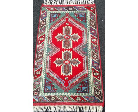 A Turkish hand-knotted oblong rug with multicoloured isometric decoration, double border with long fringe retailed by Ayasofy