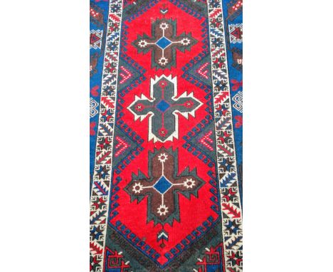 An Oriental hand-knotted wool rug with multicoloured isometric designs. double border and medium fringe, 205 x 125 cm in good