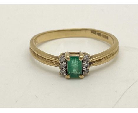 A 9ct Gold Stone Set Dress Ring, the emerald cut centre stone set between diamond set shoulders and uniform reeded band (fing