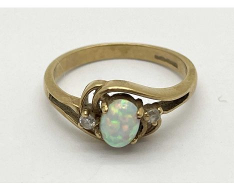 A 9ct Gold Three Stone Ring, the oval cut opal set to centre, between round cut shoulders, within decorative crossover settin