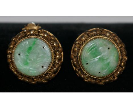 A pair of jade and silver gilt clip on earrings, circular jade panels each carved with a bird, mounted within a silver gilt f