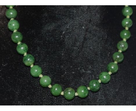 A single strand Chinese jade bead necklace, uniform globular green jade beads, each approx 10mm diameter, individually knotte