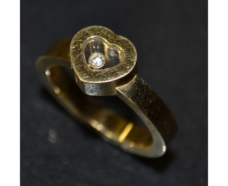 Chopard a `Happy Diamonds` ring, the glazed heart shaped mount enclosing a floating round brilliant cut diamond, on a wide ba