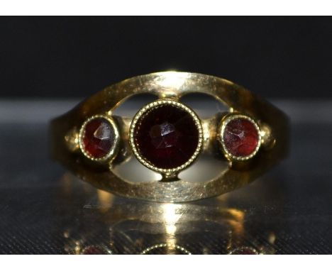 A garnet three stone ring, central round deep red garnet flanked to each side by a smaller lighter red garnet, 14ct gold shan