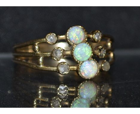 An opal and diamond ring, central row of three circular cabochon opals flashing green and blue colour play, flanked to either