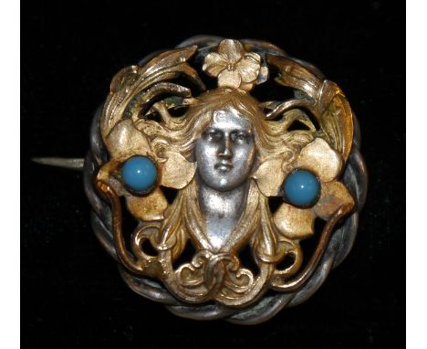 An Art Nouveau bi-metal silver and gold coloured  Maiden brooch, central mask within writhen hair and foliate surround, two t