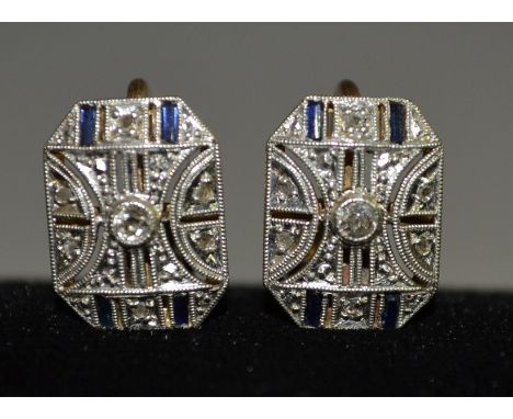 A pair of Art Deco diamond & sapphire earrings, arched cushion platforms set with a central round brilliant diamond, within a
