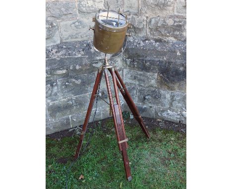 A floor standing spot light standard lamp, the brass swivel light raised on an adjustable wooden and brass tripod base