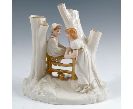 A Royal Worcester Kate Greenaway style figure group, of a boy seated on a stile and a girl leaning on the stile with two tree