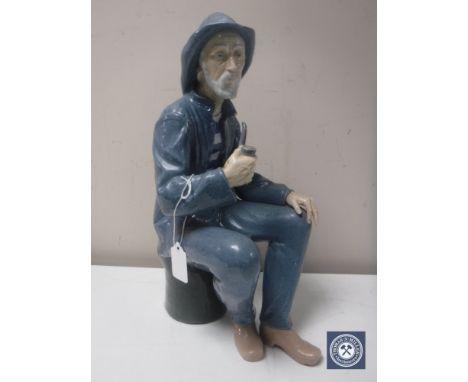 A Nao figure of a fisherman seated smoking a pipe in a matt finish, height 38 cm 