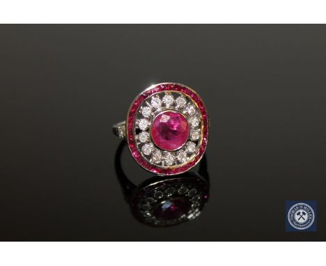 An 18ct white gold ruby and diamond cluster ring, a central oval-cut, deep red ruby weighing 1.72 carat, surrounded by eighte