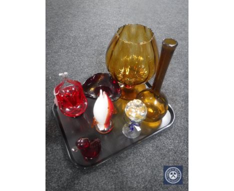 A tray of seven pieces of coloured glass ware including two amber glass vases, ruby bowl and basket, oil burner, glass fish a