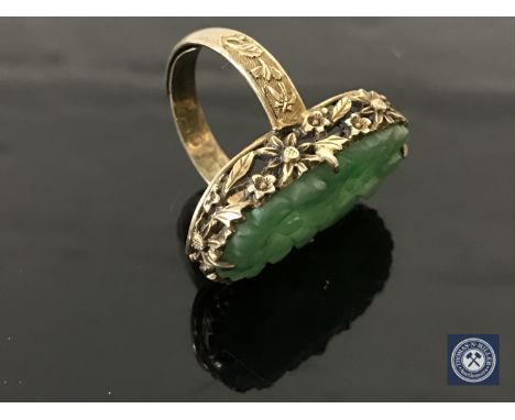 A Chinese silver gilt carved jade ring CONDITION REPORT: 7.0g. In good condition. There is a maker's mark to the shank. 