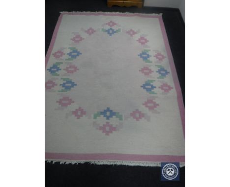 A fringed woolen carpet on pink ground 