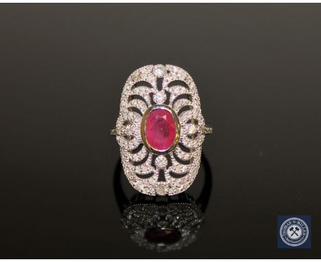 An 18ct white gold ruby and diamond cluster ring, a central oval-cut pinkish-red ruby weighing 0.91 carat, surrounded by eigh