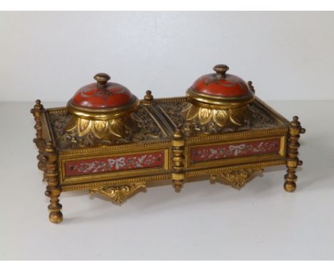 A late 19th/early 20thC Embassy style ormolu double inkstand, with domed enamel hinged covers in rust red with floral garland