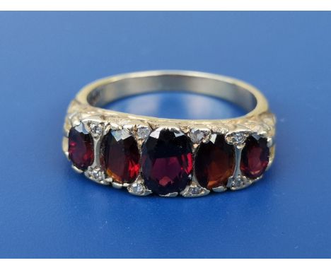 A graduated five stone garnet ring with diamond spacers in 18ct gold.  Finger size O.