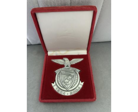 Benfica Centenary Boxed Football Emblem: 1904 - 2004 metal plaque measuring 10 x 10 cm in red suede effect case. Nice item.