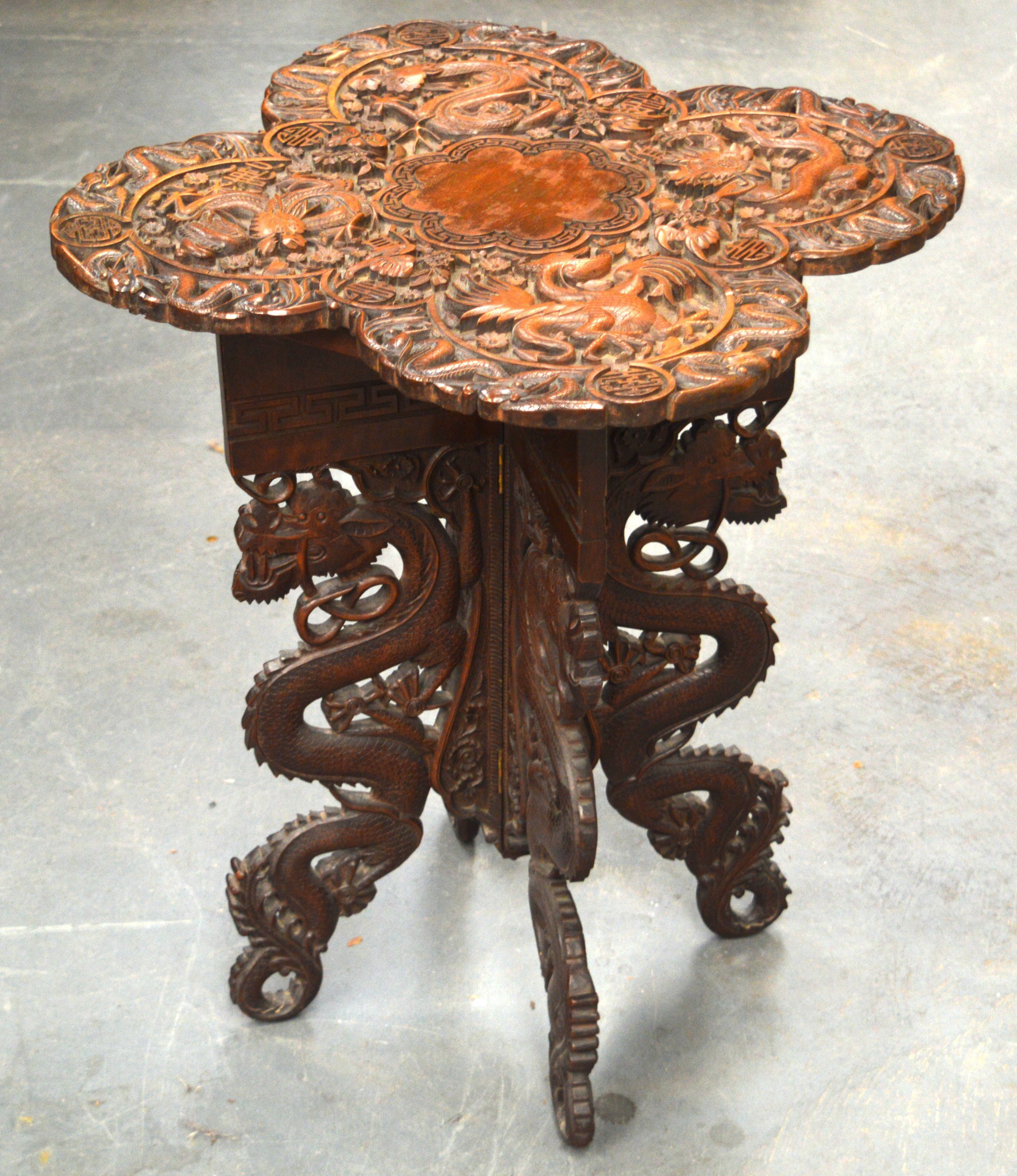 A 19TH CENTURY SOUTH EAST ASIAN CARVED WOOD DRAGON TABLE with folding base.