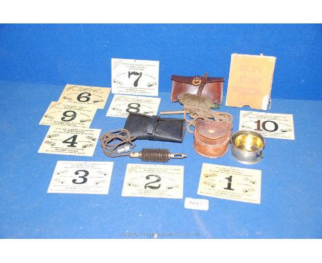 A leather Cup, two 12 bore pull throughs and ten enamel "Eley Stand Indicators" 1-10 advertising Eley cartridges from F. Morg