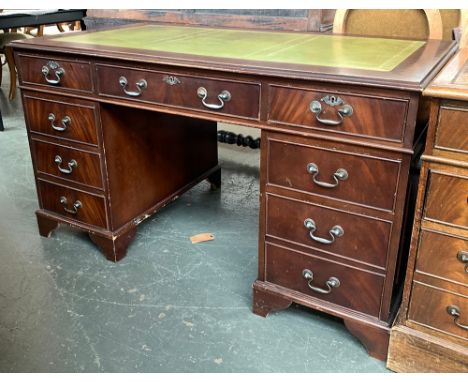 A pedestal desk, by Brights of Nettlebed, green leather inset top over the traditional arrangement of nine drawers, on bracke