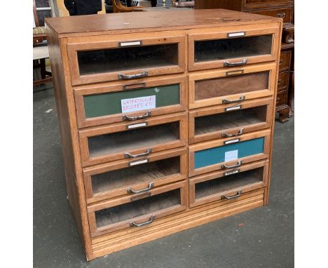 An oak haberdashery cabinet comprising ten glass fronted drawers, 91x52x93cmH (hardboard top) 